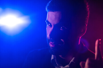 Close up photo of male face and blue light on the background.