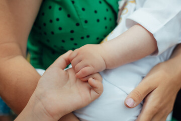 Parents' palms hold children's palms. Palms on a background of green in a black polka dot dress
