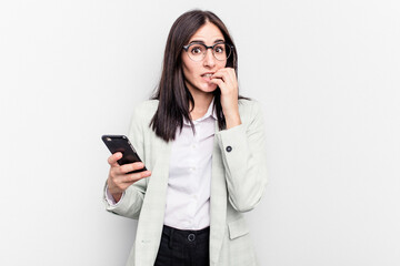 Young business caucasian woman holding mobile phone isolated on white background biting...