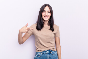 Young caucasian woman isolated on pink background person pointing by hand to a shirt copy space, proud and confident