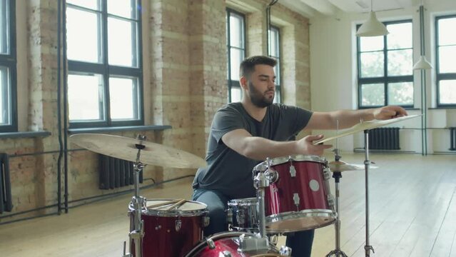 Zoom in shot of professional drummer mounting hi-hat cymbals on stand while setting up drumset in rehearsal studio