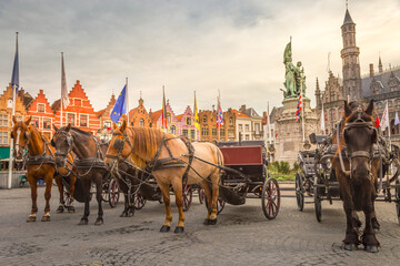 Obraz premium Bruges market square with flemish architecture and horse carriages, Belgium