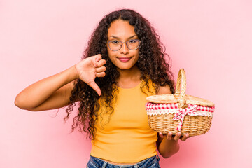 Young hispanic woman doing a picnic isolated on beige background showing a dislike gesture, thumbs down. Disagreement concept.