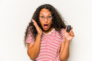 Young hispanic woman holding car keys isolated on white background surprised and shocked.