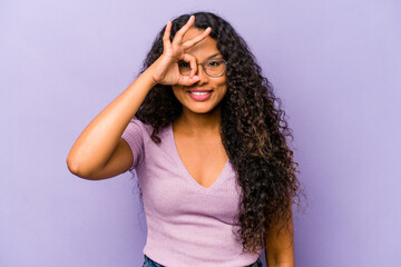 Young hispanic woman isolated on purple background excited keeping ok gesture on eye.