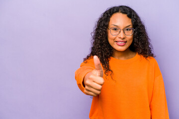 Young hispanic woman isolated on purple background smiling and raising thumb up