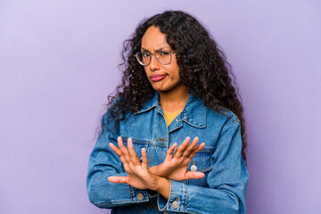 Young hispanic woman isolated on purple background doing a denial gesture