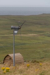 Vertical shot of a wigwam and a small windmill in The Isle of Skye, Scotland, UK © Tdal/Wirestock Creators