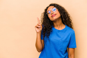Young hispanic woman isolated on beige background showing number one with finger.