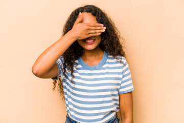 Young hispanic woman isolated on beige background covers eyes with hands, smiles broadly waiting for a surprise.