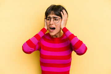 Young caucasian woman with a short hair cut isolated covering ears with hands trying not to hear too loud sound.