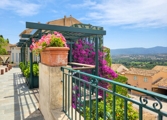 A terrace with purple bougainvillea flowers near the town square of the medieval town of Grimaud,...