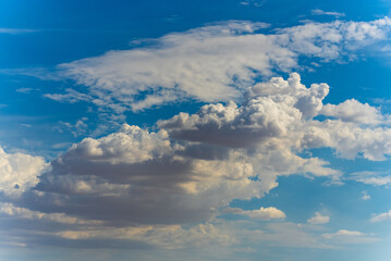 Big, fluffy clouds billowing and blowing in the blue sky 