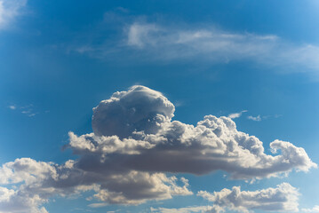 Big, fluffy clouds billowing and blowing in the blue sky 