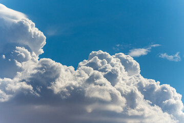 Big, fluffy clouds billowing and blowing in the blue sky 