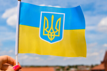 the national yellow and blue flag of Ukraine with trident on blue sky background - obrazy, fototapety, plakaty