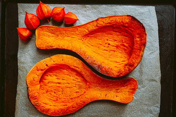 Baked pear-shaped Butternut pumpkin cut into two symmetrical halves, on baking sheet