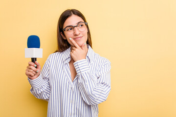 Young caucasian presenter TV woman isolated on yellow background looking sideways with doubtful and skeptical expression. - obrazy, fototapety, plakaty