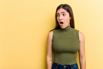 Young caucasian woman isolated on yellow background being shocked because of something she has seen.