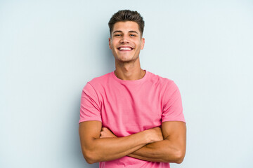 Obraz premium Young caucasian man isolated on blue background who feels confident, crossing arms with determination.
