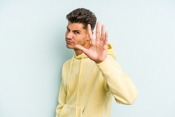 Young caucasian man isolated on blue background rejecting someone showing a gesture of disgust.