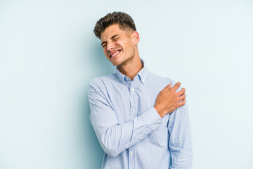 Young caucasian man isolated on blue background having a shoulder pain.