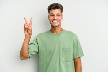 Fototapeta premium Young caucasian man isolated on white background showing victory sign and smiling broadly.