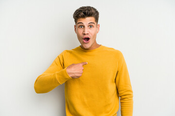 Young caucasian man isolated on white background surprised pointing with finger, smiling broadly.