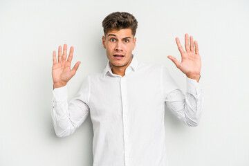 Young caucasian man isolated on white background being shocked due to an imminent danger