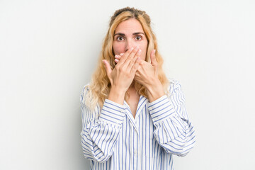 Young caucasian woman isolated on white background shocked covering mouth with hands.