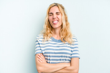 Young caucasian woman isolated on blue background funny and friendly sticking out tongue.