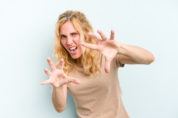 Young caucasian woman isolated on blue background upset screaming with tense hands.