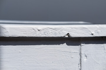 close-up of the edge of an old white rough painted table,  aged stool furniture 