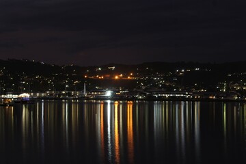 Fototapeta na wymiar Knysna at night - reflections of city lights on calm sea water