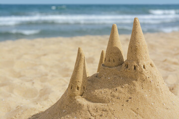 Fototapeta na wymiar Beach with sand castle near sea on sunny day. Space for text