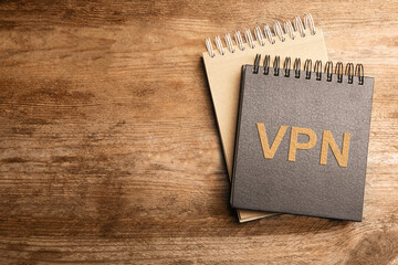 Notebook with acronym VPN and space for text on wooden table, top view. Secure network connection