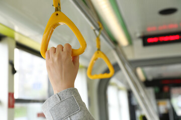Woman holding handgrip handle in public transport, closeup © New Africa