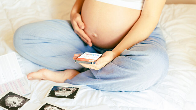 Pregnancy calendar app. Mobile pregnancy online maternity application. Pregnant mother using phone. Concept of pregnancy, maternity, expectation for baby birth.