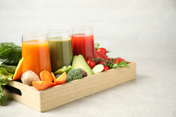 Delicious vegetable juices and fresh ingredients on light grey table