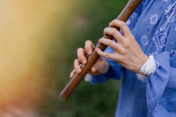 Woman playing woodwind wooden flute - ukrainian sopilka outdoors. Folk music, culture concept....