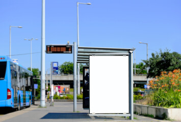 image composite of bus shelter at bus stop. blank light box and aluminum structure. white poster ad commercial poster space. green street setting. urban background. glass design. blurred background.