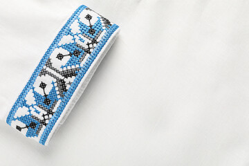 Fototapeta premium Beautiful white shirt with light blue Ukrainian national embroidery, top view. Space for text