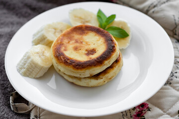 two cottage cheese pancakes with sliced banana in a white plate