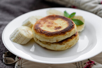 two cottage cheese pancakes with sliced banana in a white plate