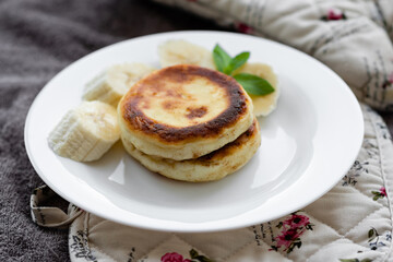 two curd fritters with sliced banana in a white plate