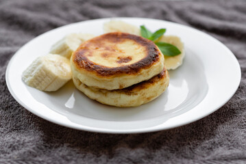 two curd fritters with sliced banana in a white plate