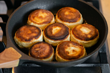 Several cottage cheese pancakes in a frying pan. Traditional breakfast or lunch. Traditional Ukrainian breakfast.