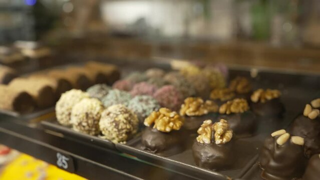 Cakes assortment in cafe showcase. Variety of beautiful desserts on shelf behind showcase glass. Pastry with different decorations and taste closeup