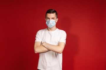 A man in a white T-shirt and protective mask crossed his arms over his chest