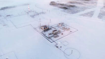 A drone flies over an oil and gas production facility during winter time during extremely low temperatures. A drone flies over the snow in Siberia where oil and gas are produced for sale to Europe